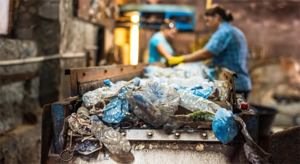 Workers sorting and processing scrap metal in industrial recycling facility